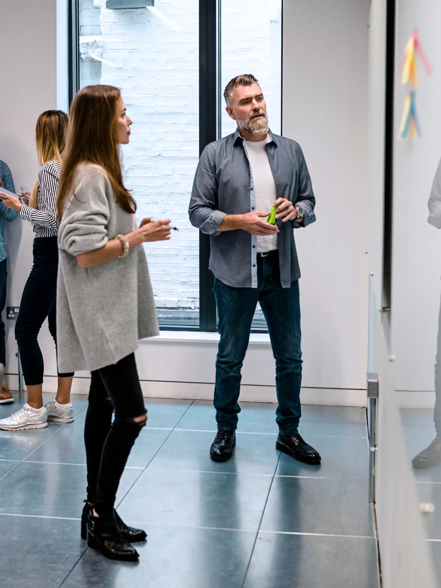 Un groupe d’adultes en discussion informelle devant un tableau blanc. Illustration d’une formation non structurée avec peu d’encadrement pédagogique.