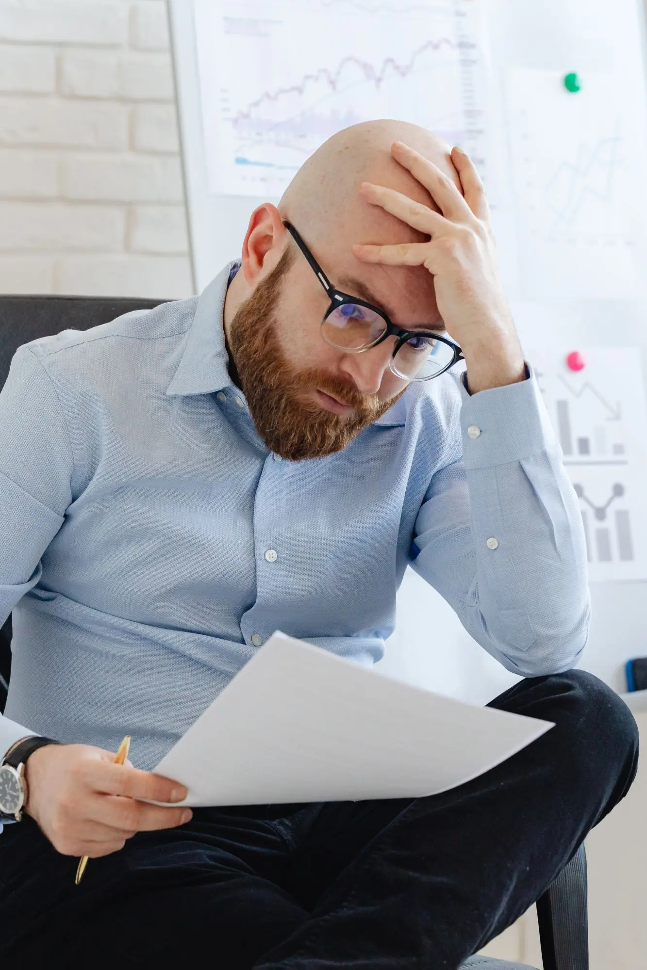 A frustrated manager sitting alone with paperwork, overwhelmed and confused by unclear or ineffective training outcomes.