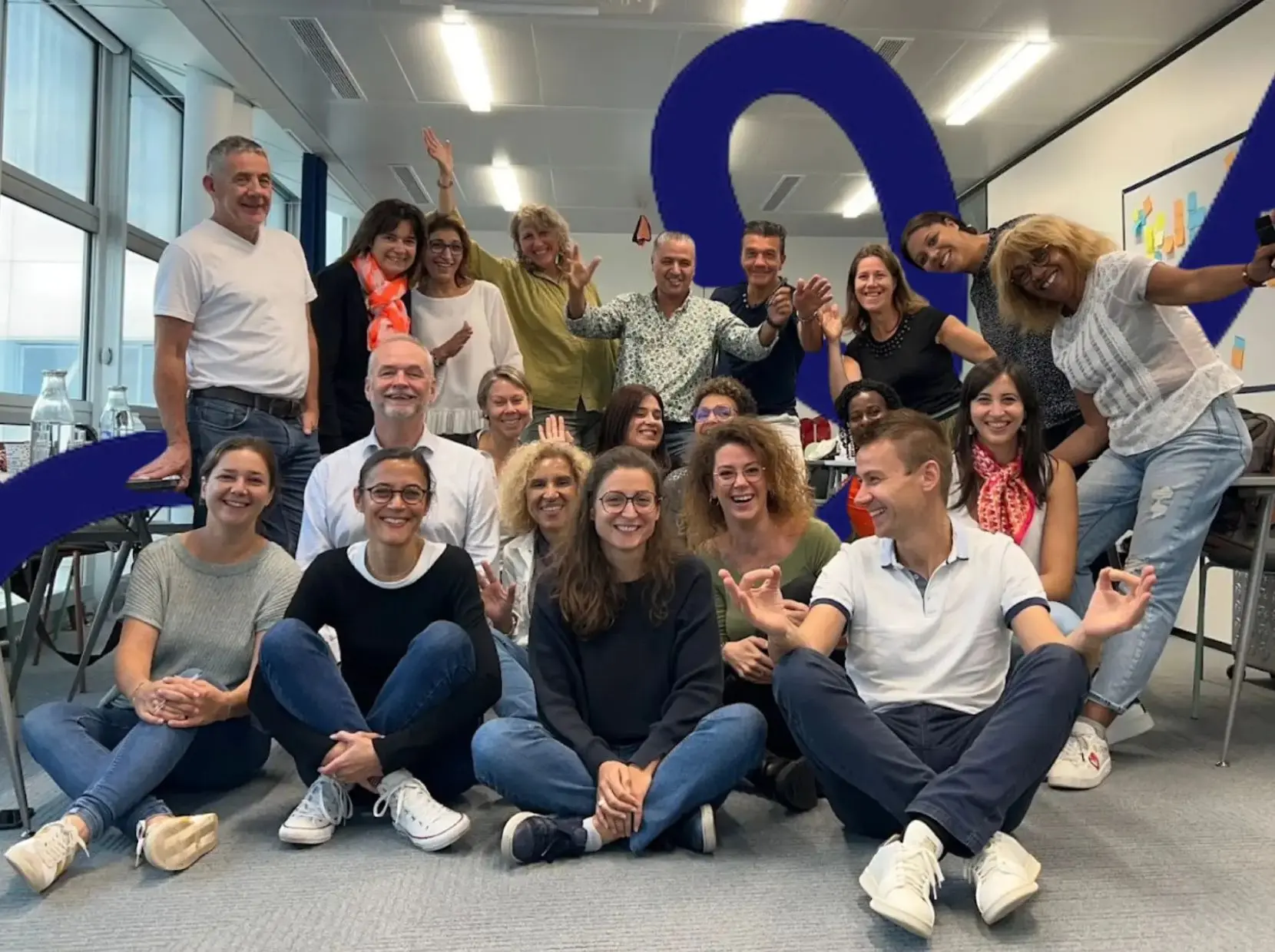 Diverse group of professionals posing together in a modern training space, celebrating the completion of a coaching-integrated management program.