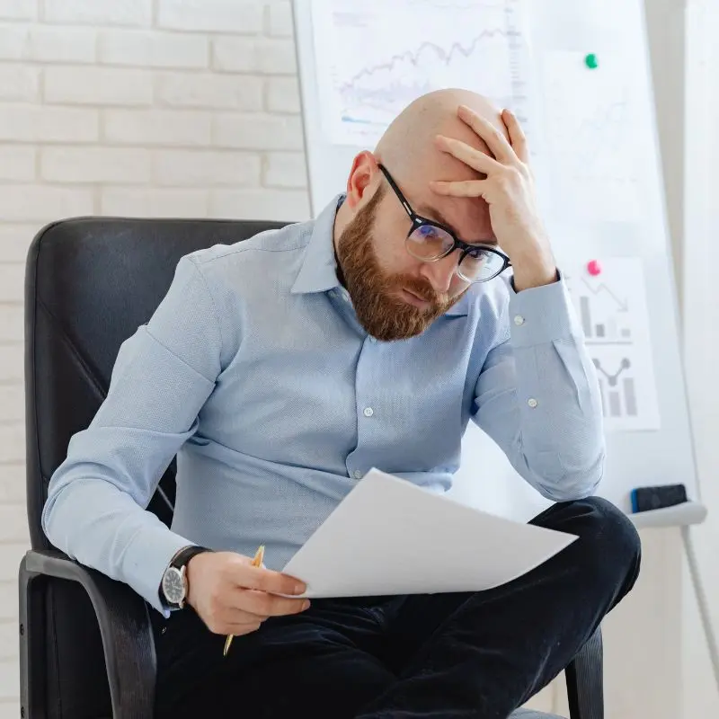 A frustrated manager sitting alone with paperwork, overwhelmed and confused by unclear or ineffective training outcomes.